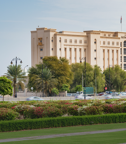 Beige building with trees and green lawn.
