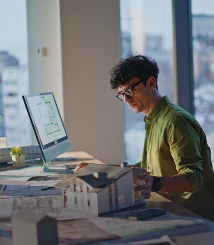 Architect working with building model and computer.