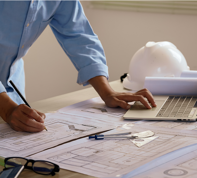 Architect reviewing blueprints at a desk.
