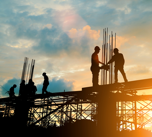 Construction workers on scaffolding at sunset.