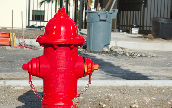 Red fire hydrant on urban street corner.